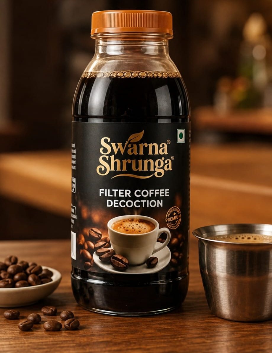 A bottle of Swarna Shrunga filter coffee decoction on a wooden table, with coffee beans and a steel tumbler